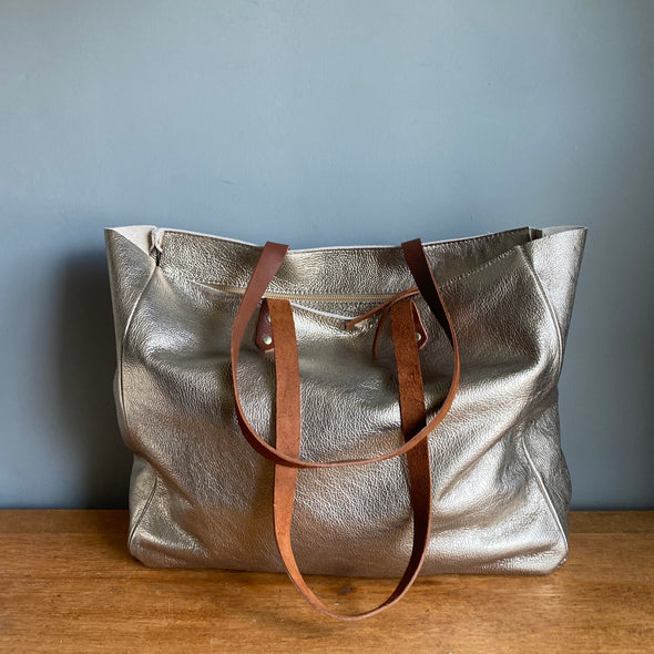 gold leather tote bag with shoulder straps and top zip