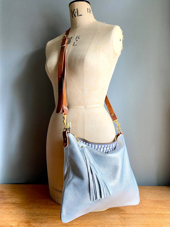 silver leather crossbody bag shown on a vintage tailor's dummy