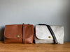 A tan brown leather handbag and a grey cowhair handbag with crossbody strap