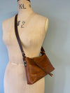 Small brown leather bag on a mannequin torso against a plain background