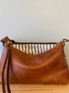 Brown leather handbag with striped lining on a wooden surface