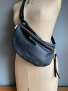 Black half moon bag in leather,  passport/travel bag shown on a vintage dressmakers dummy