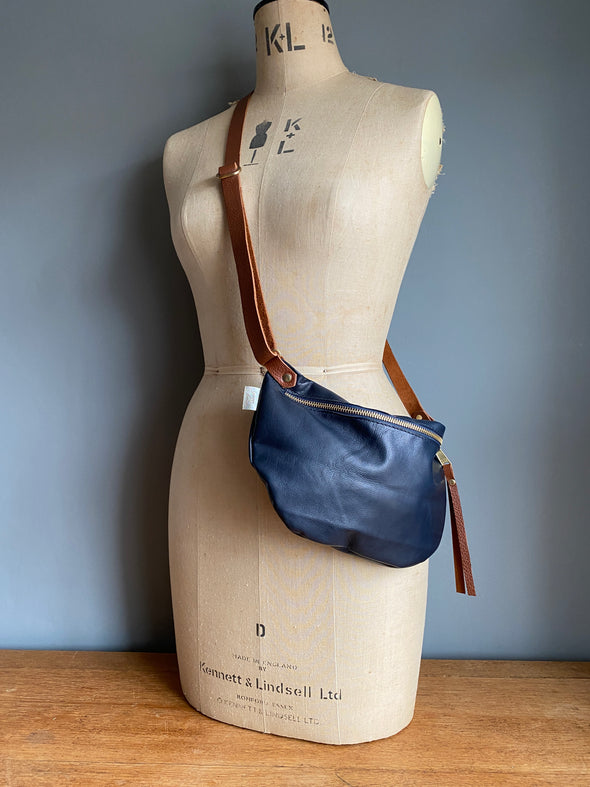 Navy half moon bag in leather,  dark blue passport/travel bag shown on a vintage dressmakers dummy