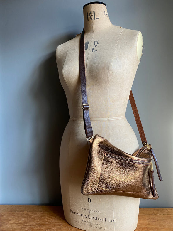 Bronze leather crossbody handbag with zipped exterior pocket and contrasting dark brown strap by Ginger and Brown shown on a vintage tailors dummy.