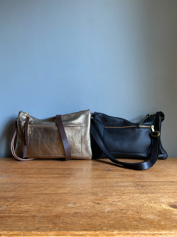 Crossbody handbag in black leather with zipped exterior pocket and adjustable crossbody strap by Ginger and Brown .