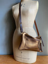 Bronze leather crossbody handbag with zipped exterior pocket and contrasting dark brown strap by Ginger and Brown shown on a vintage tailors dummy.