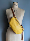 A yellow leather half moon crossbody bag worn by an antique tailors dummy