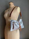 silver leather crossbody handbag with zipped exterior pocket and contrasting dark brown strap by Ginger and Brown shown on a vintage tailors dummy.