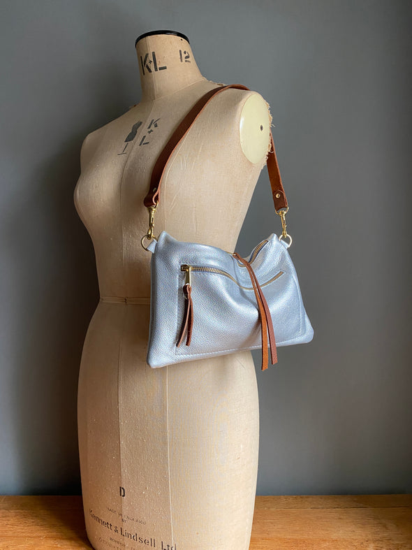 silver leather crossbody handbag with zipped exterior pocket and contrasting dark brown strap by Ginger and Brown shown on a vintage tailors dummy.