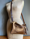 Bronze leather crossbody handbag with zipped exterior pocket and contrasting dark brown strap by Ginger and Brown shown on a vintage tailors dummy.