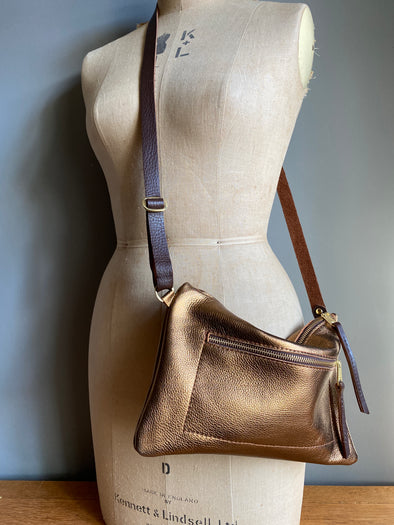 Bronze leather crossbody handbag with zipped exterior pocket and contrasting dark brown strap by Ginger and Brown shown on a vintage tailors dummy.