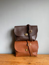 Brown leather handbags shown on a wooden table 