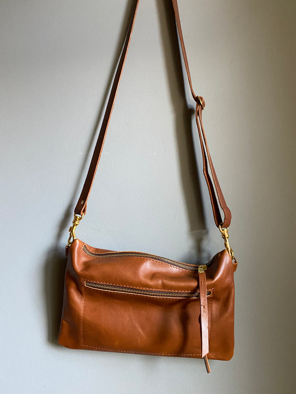 Crossbody handbag in tan brown leather with zipped exterior pocket and adjustable crossbody strap by Ginger and Brown .