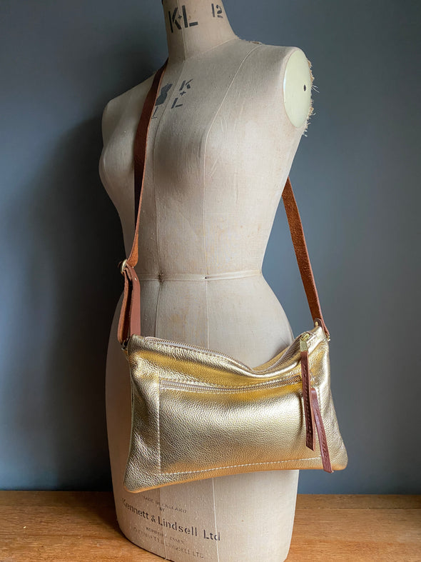 Gold leather crossbody handbag with zipped exterior pocket by Ginger and Brown shown on a vintage tailors dummy.