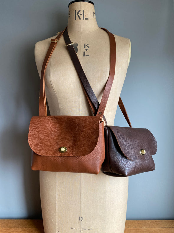 Brown leather satchel bag in tan brown and dark brown shown on a vintage tailors dummy