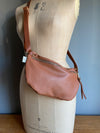 Tan brown half moon bag in leather, a butterscotch brown passport/travel bag shown on a vintage dressmakers dummy