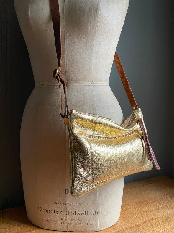 Gold leather crossbody handbag with zipped exterior pocket by Ginger and Brown shown on a vintage tailors dummy.