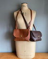 Brown leather satchel bag in tan brown and dark brown shown on a vintage tailors dummy