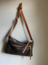 Crossbody handbag in dark brown leather with zipped exterior pocket and contrasting brown strap by Ginger and Brown shown hanging from a hook.