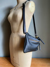 Crossbody handbag in black leather with zipped exterior pocket and adjustable crossbody strap by Ginger and Brown shown on a vintage tailor's dummy. 