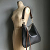 Dark brown leather purse with a shoulder strap shown on a tailor's vintage dummy