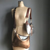 Bronze leather purse with crossbody strap and a soft gold handbag shown on a vintage tailor's dummy