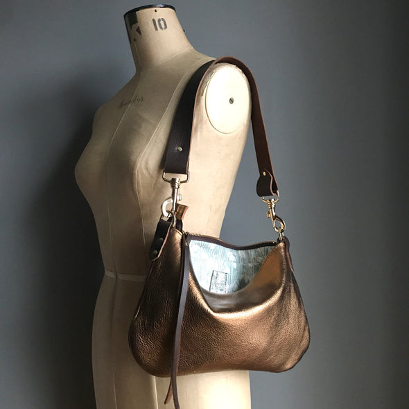 Bronze leather purse with shoulder strap shown on a vintage tailor's dummy