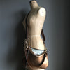 Bronze leather purse with shoulder strap shown on a vintage tailor's dummy